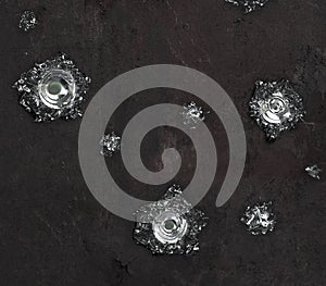 Silver bullet hole on black textured wall