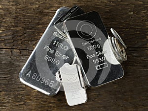 Silver cast and minted bars and coins on the background of wood texture