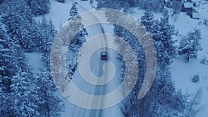 Silver car driving on winter country road in snowy forest