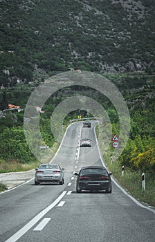 Silver car overtaking a slower black one on a straight before a corner. Dangeour overtake in forbidden area, possibility of