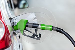 Silver car refuelling at the gas station, the concept of fuel energy