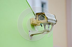 Silver CCTV Camera on the green wall Closed Circuit Television camera on green background