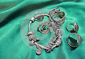Silver charm bracelet with charms and rings on the green silk