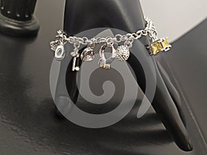 Silver charm bracelet with pendants on mannequin hand
