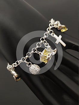 Silver charm bracelet with pendants on mannequin hand