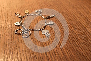 Silver charm bracelet on a scratched wooden background