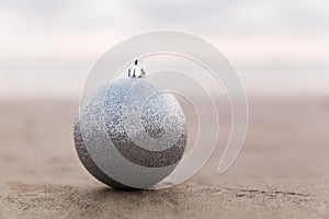 Silver Christmas ball at the beach in sepia tone, holiday concept