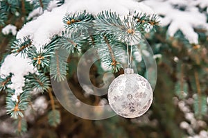 Silver Christmas ball on a snow-covered tree branch