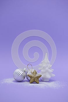 Silver Christmas balls, gold star and white Christmas tree on purple background with copy space. Concept vertical winter card