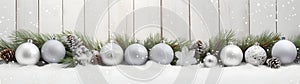 Silver Christmas balls, stars and trees in a row with spruce branches.