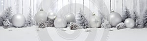 Silver Christmas balls, stars and trees in a row with spruce branches.