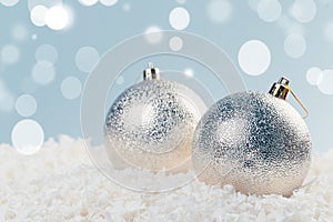 Silver Christmas balls in white snow on a blue background with bokeh lights. happy new year card