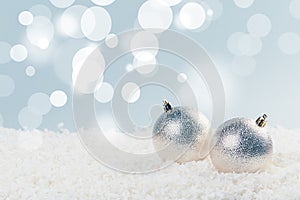 Silver Christmas balls in white snow on a blue background with bokeh lights. happy new year card