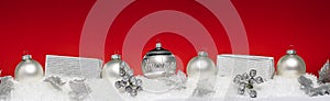Silver Christmas balls with xmas gift boxes in a row on snow.Red background