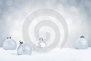 Silver Christmas baubles on snow with