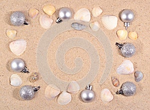 Silver Christmas decorations and seashells on a beach sand