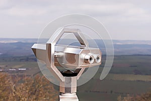 Silver Coin Operated binocular viewer with landscape in the background