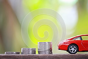 Silver coin of pile with red car model in concept savings to buy