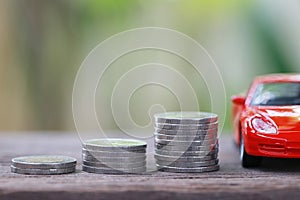 Silver coin of pile with red car model in concept savings to buy