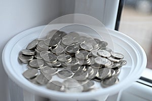 Silver coins on a white saucer. The accumulation of coins. Picking up money for vacation