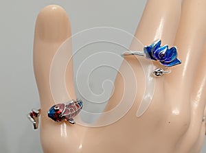Silver color bijou rings with enamel fish and lotus flower ornament on mannequin hand