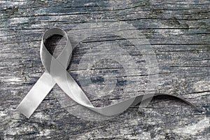 Silver color ribbon on old aged wood isolated with clipping path for Parkinson`s disease awareness and Brain cancer tumor