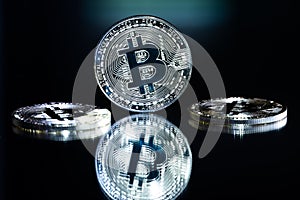 Silver colored bitcoin token with reflection