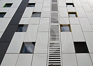 silver colored metal cladding panels on a modern building with repeating windows and geometric grid design