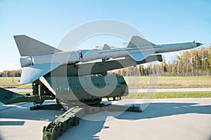 A silver-colored rocket with a launcher on the background of a forest and a blue sky. Military equipment planes missiles