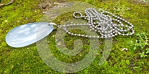 Silver colour chain with pendant & x28;blue colour stone& x29; lying on the ground.