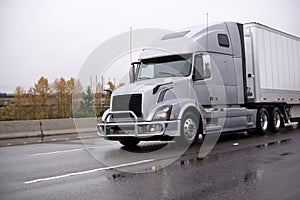 Silver big rig semi truck with grille guard transporting dry van