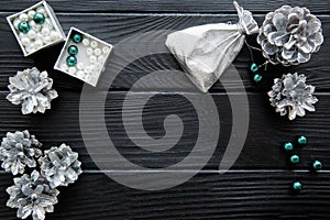 Silver cones and emerald green beads on black table. Space for t