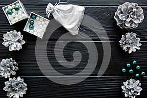 Silver cones and emerald green beads on black table. Space for t