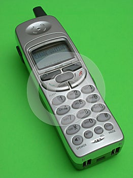 Silver cordless telephone on green backdrop