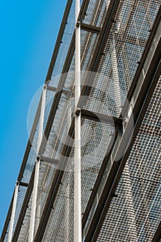 Silver corrugated metal wall seen from below with clear blue sky