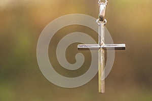 Silver cross on a background of nature. Concept for faith, spirituality and religion.