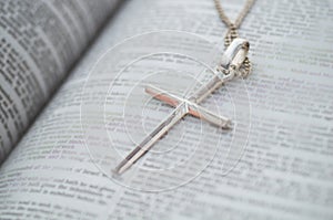 Silver cross on bible background. Concept for faith, spirituality and religion.