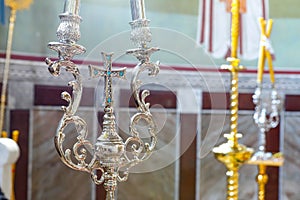 Silver cross with blue stones between two candlesticks, an attribute of the Orthodox Church.