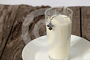 Silver cross and a glass full of milk on a wooden table in the kitchen