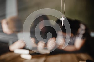 Silver cross in the necklace with praying family background