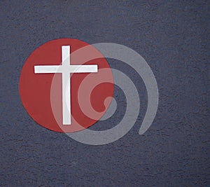 Silver Cross on red circle.