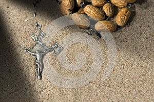 Silver Crucifix with Rosary Beads on Sand