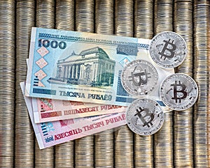 Silver crypto coins bitcoin BTC, paper Belarusian ruble. Metal coins are laid out in a flat background, close-up view from top, cr