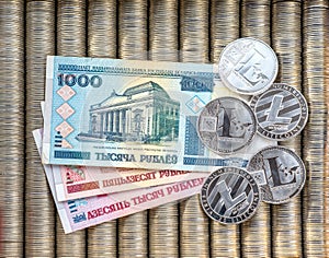 Silver crypto coins Litecoin LTC, paper denominations Belarusian ruble. Metal coins are laid out in a flat background, close-up vi