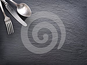 Silver cutlery on a dark background.