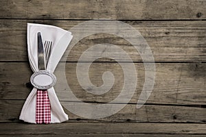 Silver cutlery in red and white checked with napkin on an old wooden background.