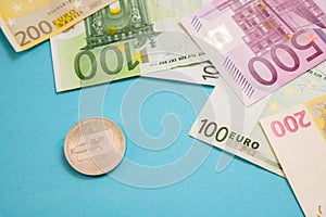 Silver Dash coin next to Euro bank notes on blue background. Digital currency, block chain market. Euro bills next to crypto coin