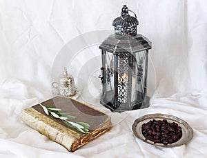 A silver decorative cup of tea and glowing Moroccan lantern on table background. Iftar dinner. Ramadan Kareem greeting