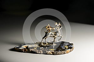 Silver deer with gold antlers and small gold nuggets spread on the surface of   agate pedestal