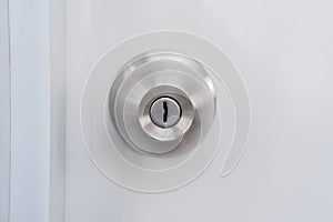 A silver doorknob mounted on a white door.